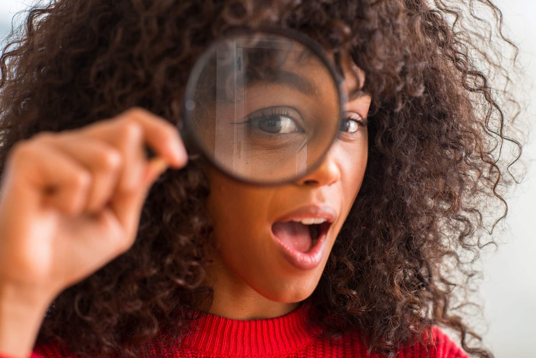 Woman Looking through magnifying glass with excited look on her face